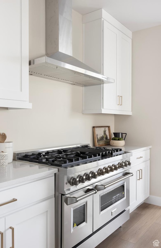 1562 E 3900 S Unit 106, Millcreek, UT 84124 - kitchen featuring range with two ovens, wall chimney range hood, white cabinets, light countertops, and light wood-style floors