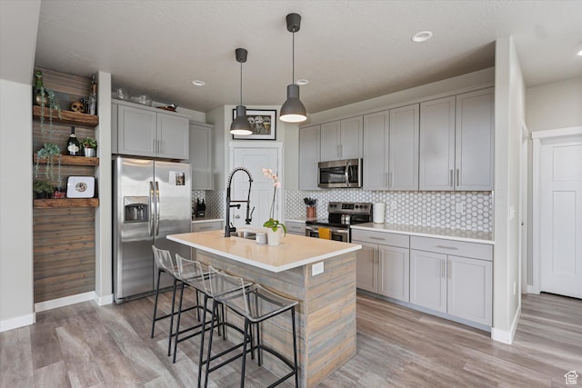 702 E 330 N, Vineyard, UT 84059 - kitchen with stainless steel appliances, gray cabinets, a kitchen island with sink, a breakfast bar area, and backsplash