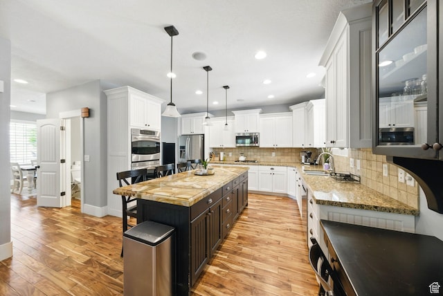 10416 S Vermillion Dr W, South Jordan, UT 84009 - kitchen with appliances with stainless steel finishes, white cabinets, light wood-style floors, backsplash, and recessed lighting