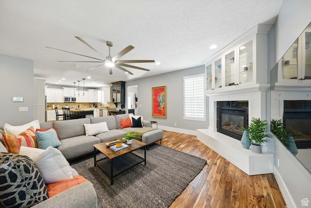 10416 S Vermillion Dr W, South Jordan, UT 84009 - living area with a fireplace, ceiling fan, recessed lighting, light wood finished floors, and baseboards