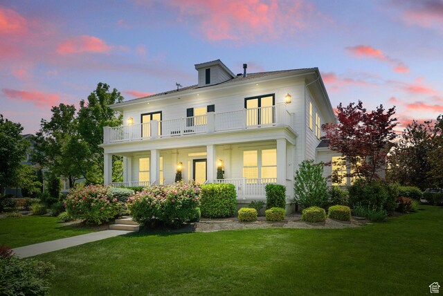 10416 S Vermillion Dr W, South Jordan, UT 84009 - back of property at dusk featuring a balcony, covered porch, and a lawn