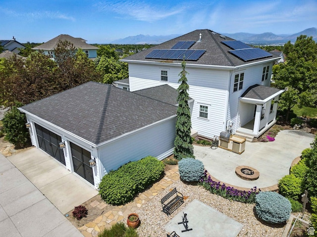 10416 S Vermillion Dr W, South Jordan, UT 84009 - view of side of home featuring a shingled roof, a mountain view, an outdoor fire pit, and solar panels