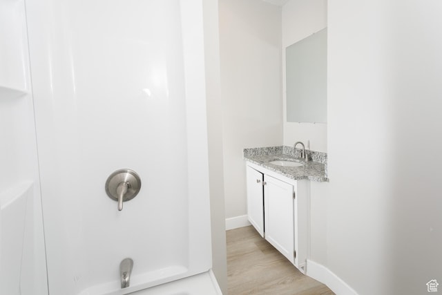 1623 W Claybourne Ave S, West Valley City, UT 84119 - bathroom featuring vanity, wood finished floors, baseboards, a shower, and a tub to relax in