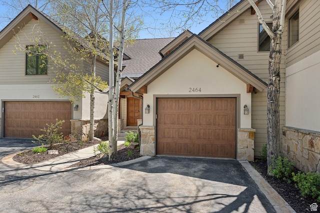 2464 Deer Lake Dr, Park City, UT 84060 - view of front of property with driveway, stone siding, a shingled roof, an attached garage, and stucco siding
