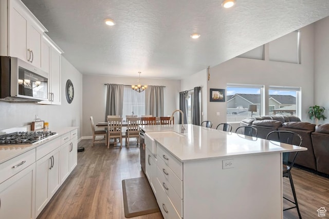 2076 E Granite Ln N Unit 145, Eagle Mountain, UT 84005 - kitchen featuring appliances with stainless steel finishes, a breakfast bar, a chandelier, plenty of natural light, and a textured ceiling
