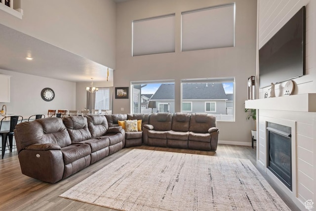 2076 E Granite Ln N Unit 145, Eagle Mountain, UT 84005 - living area featuring wood finished floors, a chandelier, a towering ceiling, a glass covered fireplace, and baseboards