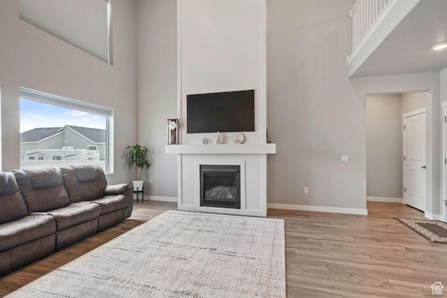 2076 E Granite Ln N Unit 145, Eagle Mountain, UT 84005 - living room featuring a towering ceiling, wood finished floors, a fireplace, and baseboards