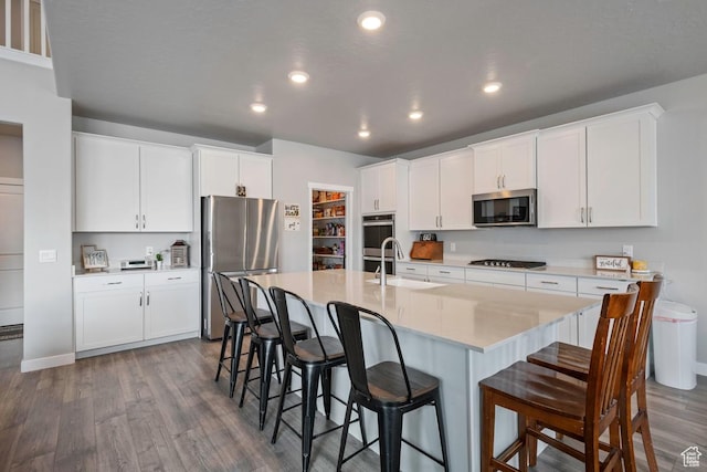 2076 E Granite Ln N Unit 145, Eagle Mountain, UT 84005 - kitchen featuring appliances with stainless steel finishes, a sink, dark wood-style flooring, a kitchen bar, and recessed lighting