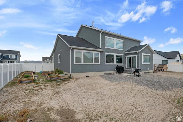 2076 E Granite Ln N Unit 145, Eagle Mountain, UT 84005 - back of property featuring a vegetable garden, stucco siding, and entry steps