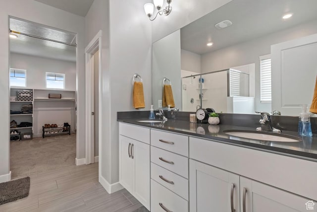 2076 E Granite Ln N Unit 145, Eagle Mountain, UT 84005 - bathroom with a stall shower, double vanity, a walk in closet, wood finished floors, and recessed lighting