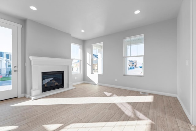 9806 N Willowbank Dr, Highland, UT 84003 - unfurnished living room with light wood-style flooring, a glass covered fireplace, baseboards, and recessed lighting