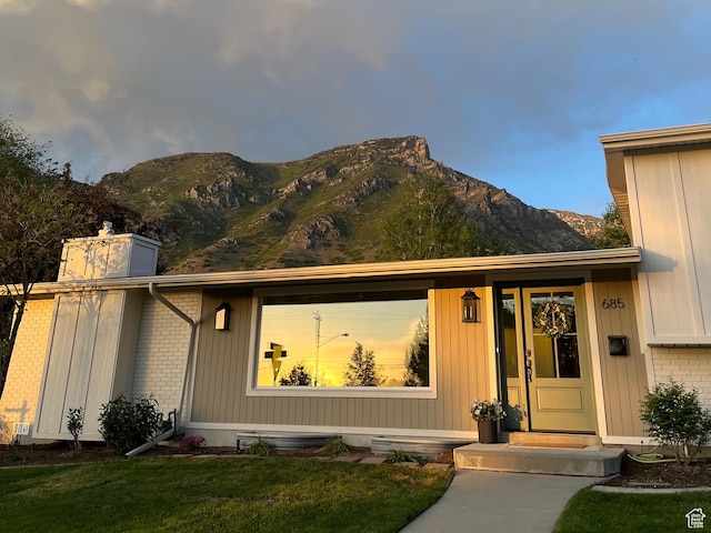 685 S Idaho Ave E, Provo, UT 84606 - doorway to property featuring a mountain view, brick siding, a lawn, and a chimney