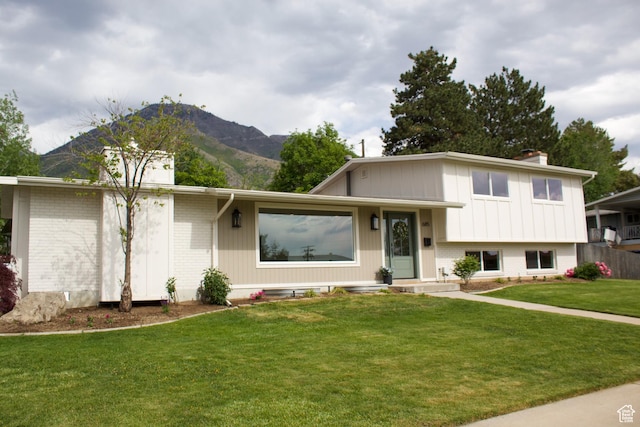 685 S Idaho Ave E, Provo, UT 84606 - tri-level home featuring brick siding, a chimney, a front lawn, and a mountain view
