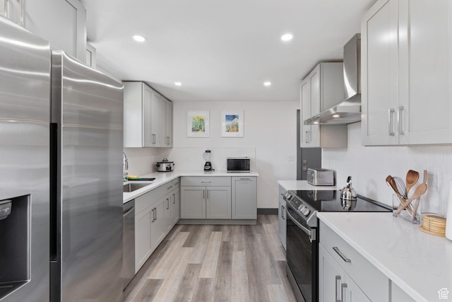 3649 S Hawkeye St, West Valley City, UT 84120 - kitchen featuring appliances with stainless steel finishes, wall chimney exhaust hood, a sink, light wood-type flooring, and light countertops