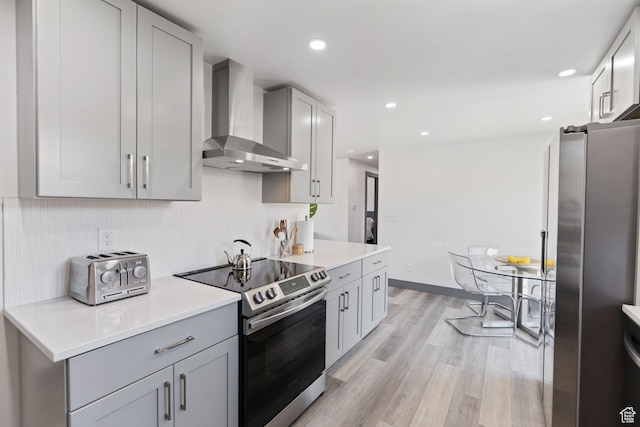 3649 S Hawkeye St, West Valley City, UT 84120 - kitchen with wall chimney exhaust hood, appliances with stainless steel finishes, light countertops, light wood-style floors, and gray cabinetry