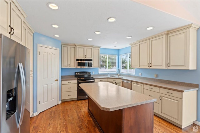 2718 W Southpointe Rd, South Jordan, UT 84095 - kitchen with stainless steel appliances, cream cabinets, light wood finished floors, a sink, and a center island