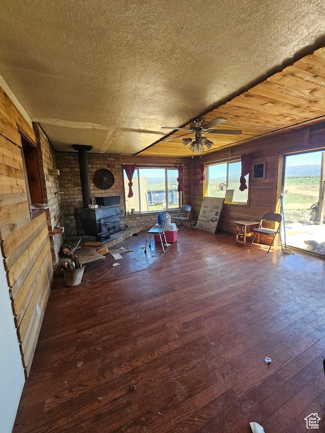 44600 W Hwy 40, Fruitland, UT 84027 - living area featuring a ceiling fan, a wood stove, wood-type flooring, wood walls, and a textured ceiling