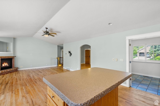 1291 E 5630 S, South Ogden, UT 84403 - kitchen featuring arched walkways, a ceiling fan, a fireplace, light wood finished floors, and a center island