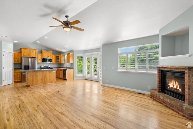 1291 E 5630 S, South Ogden, UT 84403 - kitchen featuring appliances with stainless steel finishes, a kitchen island, light wood-style flooring, vaulted ceiling, and a brick fireplace