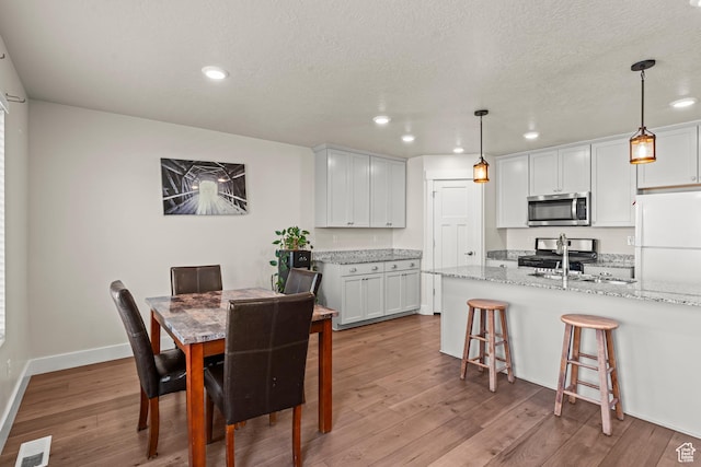3932 S Sennie Dr W, Magna, UT 84044 - dining area with recessed lighting, wood finished floors, baseboards, and a textured ceiling
