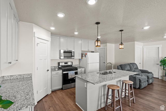 3932 S Sennie Dr W, Magna, UT 84044 - kitchen with appliances with stainless steel finishes, a sink, open floor plan, dark wood finished floors, and a kitchen bar