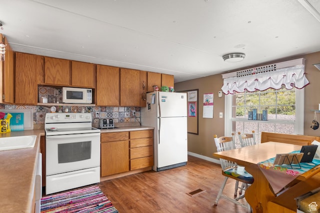 3058 S Edgemont Dr Unit 253, 54, Garden City, UT 84028 - kitchen featuring white appliances, backsplash, brown cabinetry, light wood-type flooring, and light countertops
