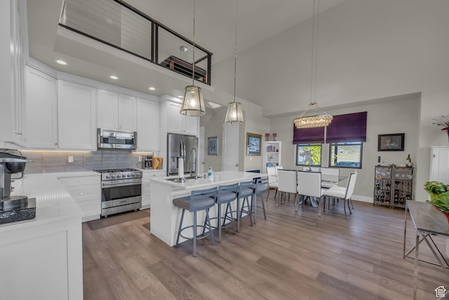 9984 N Rail Loop Unit 29, Heber City, UT 84032 - kitchen featuring appliances with stainless steel finishes, high vaulted ceiling, a kitchen bar, light countertops, and white cabinetry