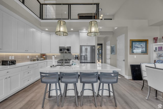 9984 N Rail Loop Unit 29, Heber City, UT 84032 - kitchen featuring appliances with stainless steel finishes, tasteful backsplash, white cabinets, light countertops, and a kitchen bar