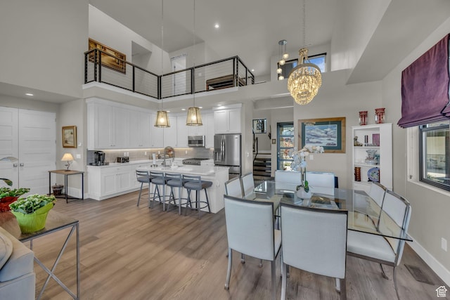 9984 N Rail Loop Unit 29, Heber City, UT 84032 - dining area featuring a high ceiling, light wood finished floors, a chandelier, healthy amount of natural light, and baseboards