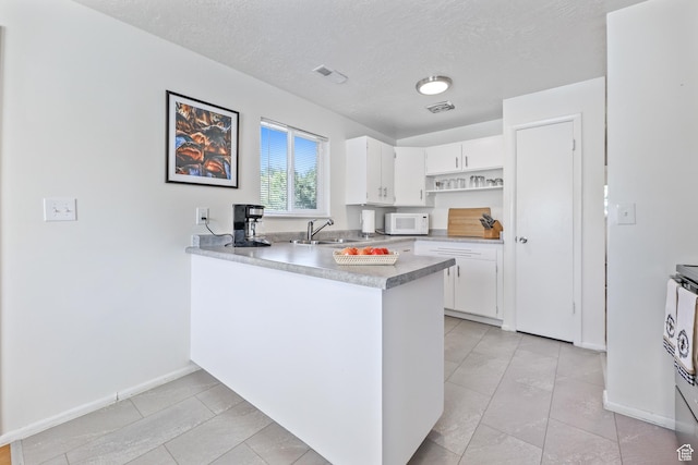180 W Vine St, Tooele, UT 84074 - kitchen featuring white microwave, open shelves, white cabinets, a peninsula, and light countertops