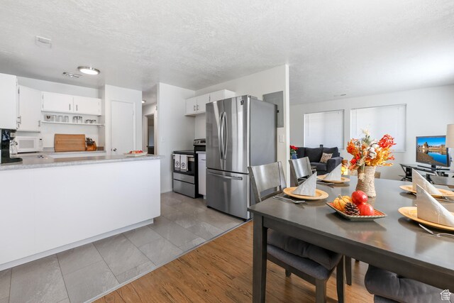 180 W Vine St, Tooele, UT 84074 - kitchen with stainless steel appliances, white cabinets, light countertops, a textured ceiling, and a peninsula