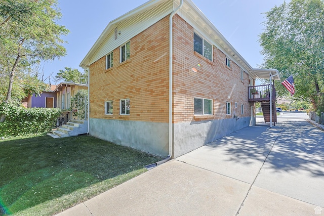 180 W Vine St, Tooele, UT 84074 - view of property exterior with stairway, a lawn, brick siding, a patio, and a deck
