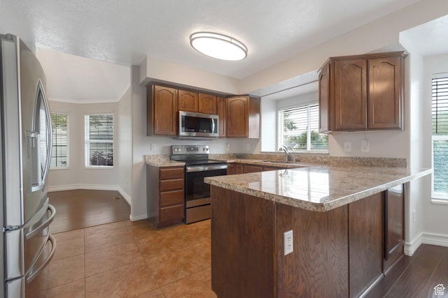494 E High Berry Ln S, Draper, UT 84020 - kitchen featuring appliances with stainless steel finishes, a sink, a peninsula, baseboards, and brown cabinetry