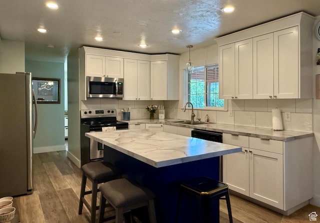 1273 W 1500 S, Vernal, UT 84078 - kitchen featuring appliances with stainless steel finishes, a sink, a breakfast bar, white cabinets, and recessed lighting