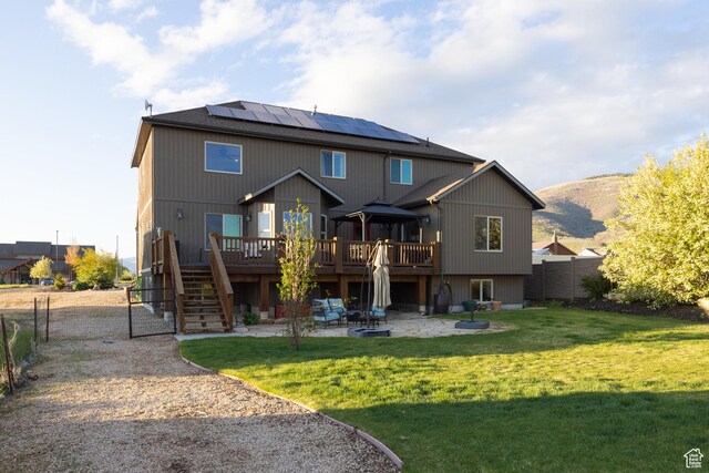 300 E 400 S, Kamas, UT 84036 - rear view of house featuring a patio, a deck with mountain view, roof mounted solar panels, stairway, and a gate