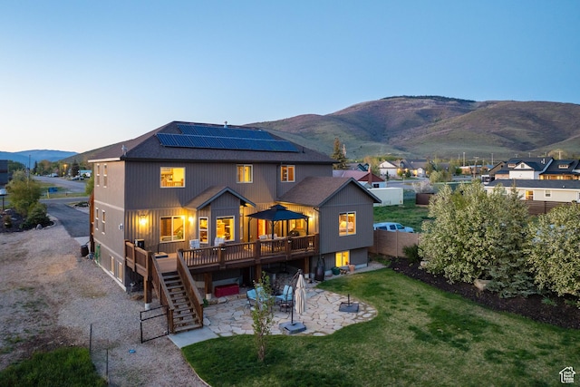 300 E 400 S, Kamas, UT 84036 - rear view of house featuring a patio area, a deck with mountain view, roof mounted solar panels, stairway, and roof with shingles