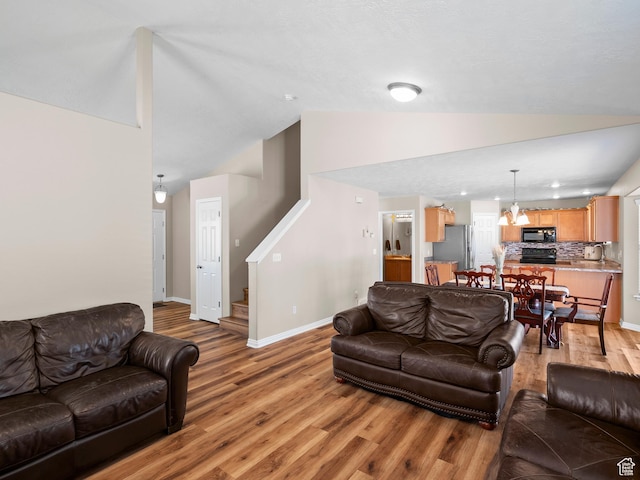 8552 S Maul Oak Dr, West Jordan, UT 84081 - living area with lofted ceiling, light wood finished floors, baseboards, stairway, and a chandelier