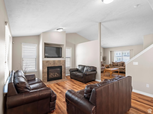 8552 S Maul Oak Dr, West Jordan, UT 84081 - living area with wood finished floors, lofted ceiling, a fireplace, baseboards, and a textured ceiling