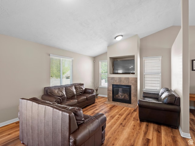 8552 S Maul Oak Dr, West Jordan, UT 84081 - living area with vaulted ceiling, a tile fireplace, light wood finished floors, baseboards, and a textured ceiling