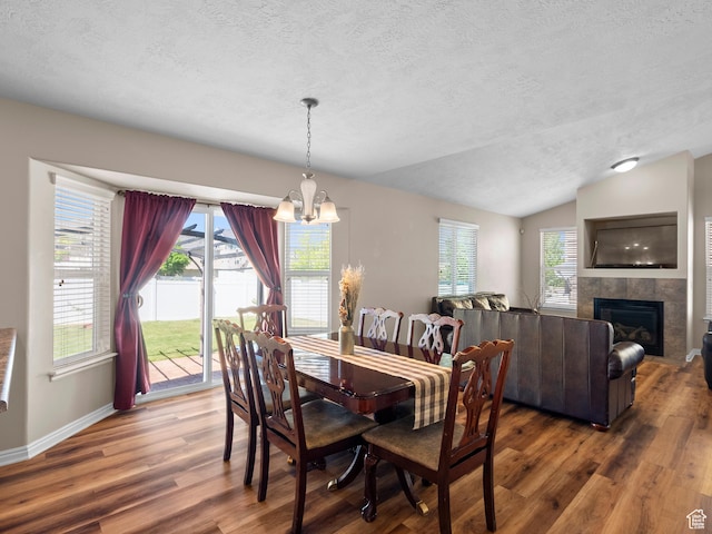 8552 S Maul Oak Dr, West Jordan, UT 84081 - dining space with a textured ceiling, wood finished floors, a fireplace, a chandelier, and lofted ceiling