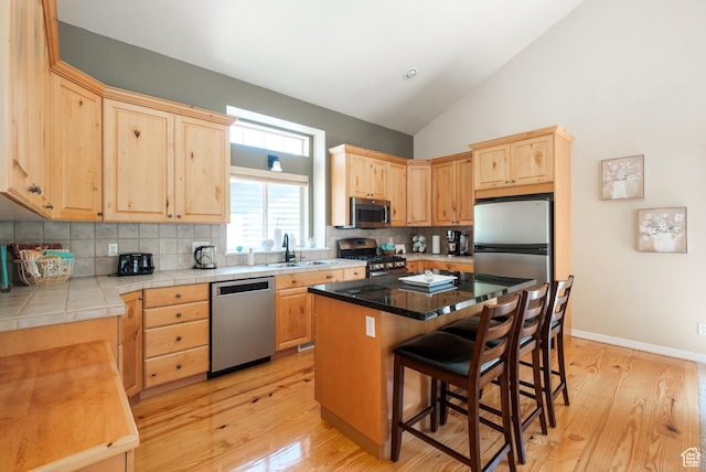 7403 Brook Hollow Loop Rd, Park City, UT 84098 - kitchen featuring stainless steel appliances, light brown cabinetry, a breakfast bar area, decorative backsplash, and light wood-style floors