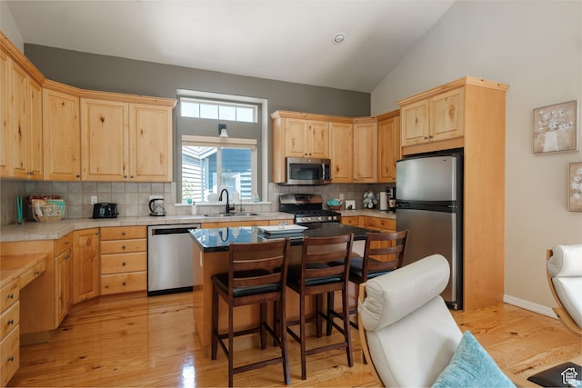 7403 Brook Hollow Loop Rd, Park City, UT 84098 - kitchen featuring stainless steel appliances, light brown cabinets, a sink, a breakfast bar, and vaulted ceiling
