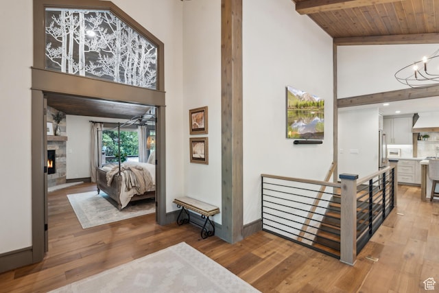 3058 Elk Run Dr W, Park City, UT 84098 - hall featuring a towering ceiling, light wood-type flooring, an upstairs landing, a chandelier, and a wooden ceiling with exposed beams