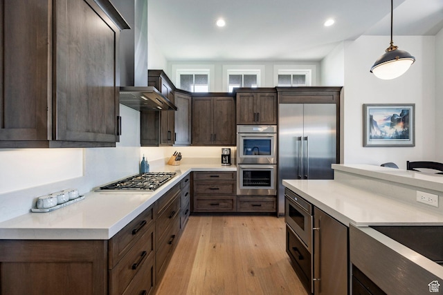 201 N Kings Peak Ct Unit Cp-23, Heber City, UT 84032 - kitchen featuring built in appliances, dark brown cabinetry, light wood finished floors, wall chimney range hood, and light countertops