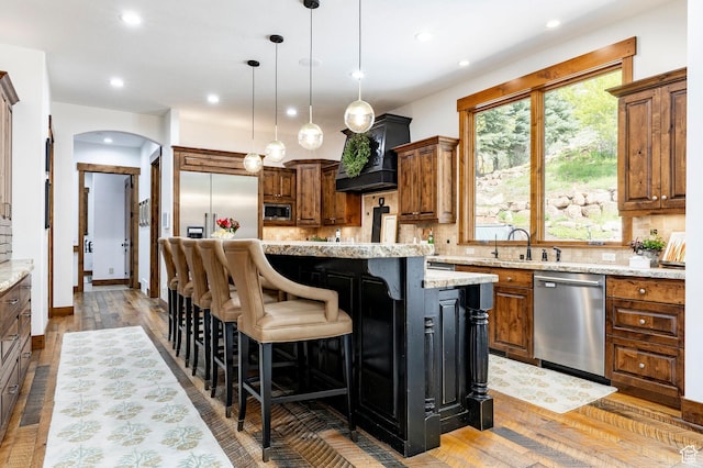 2938 Daybreaker Dr, Park City, UT 84098 - kitchen with stainless steel appliances, backsplash, a kitchen island, arched walkways, and light wood-style flooring