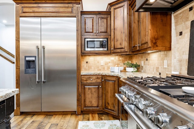 2938 Daybreaker Dr, Park City, UT 84098 - kitchen featuring built in appliances, backsplash, light stone counters, and under cabinet range hood