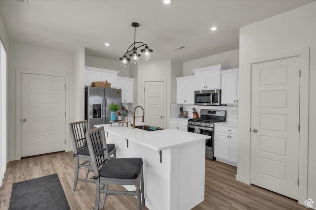 758 W Slate Ln, St George, UT 84790 - kitchen featuring appliances with stainless steel finishes, a sink, decorative backsplash, white cabinetry, and a center island with sink