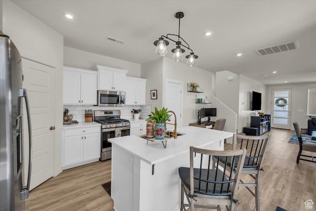 758 W Slate Ln, St George, UT 84790 - kitchen with appliances with stainless steel finishes, open floor plan, backsplash, light wood-style floors, and a kitchen breakfast bar