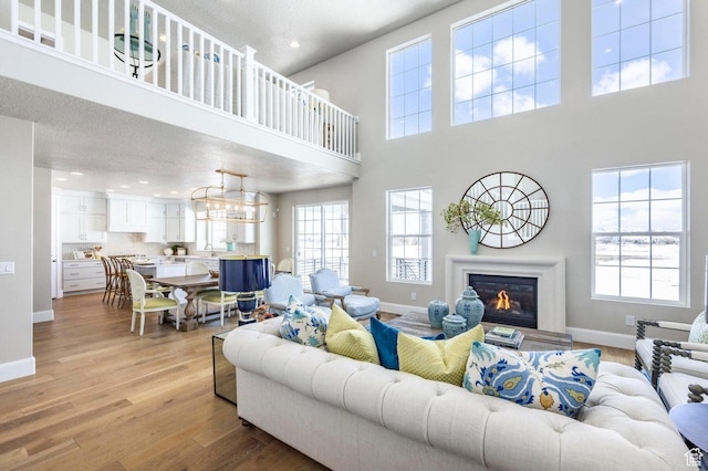 1460 Rocky Mountain Way Unit 223, Francis, UT 84036 - living room featuring baseboards, a towering ceiling, light wood finished floors, recessed lighting, and a glass covered fireplace
