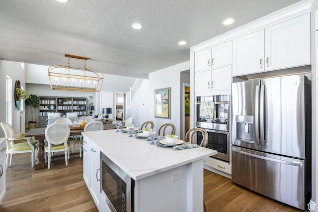 1460 Rocky Mountain Way Unit 223, Francis, UT 84036 - kitchen featuring appliances with stainless steel finishes, a textured ceiling, a center island, white cabinets, and dark wood-style floors